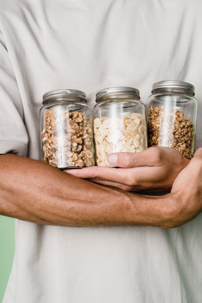 Person Holding Clear Glass Jar With White and Brown Beans